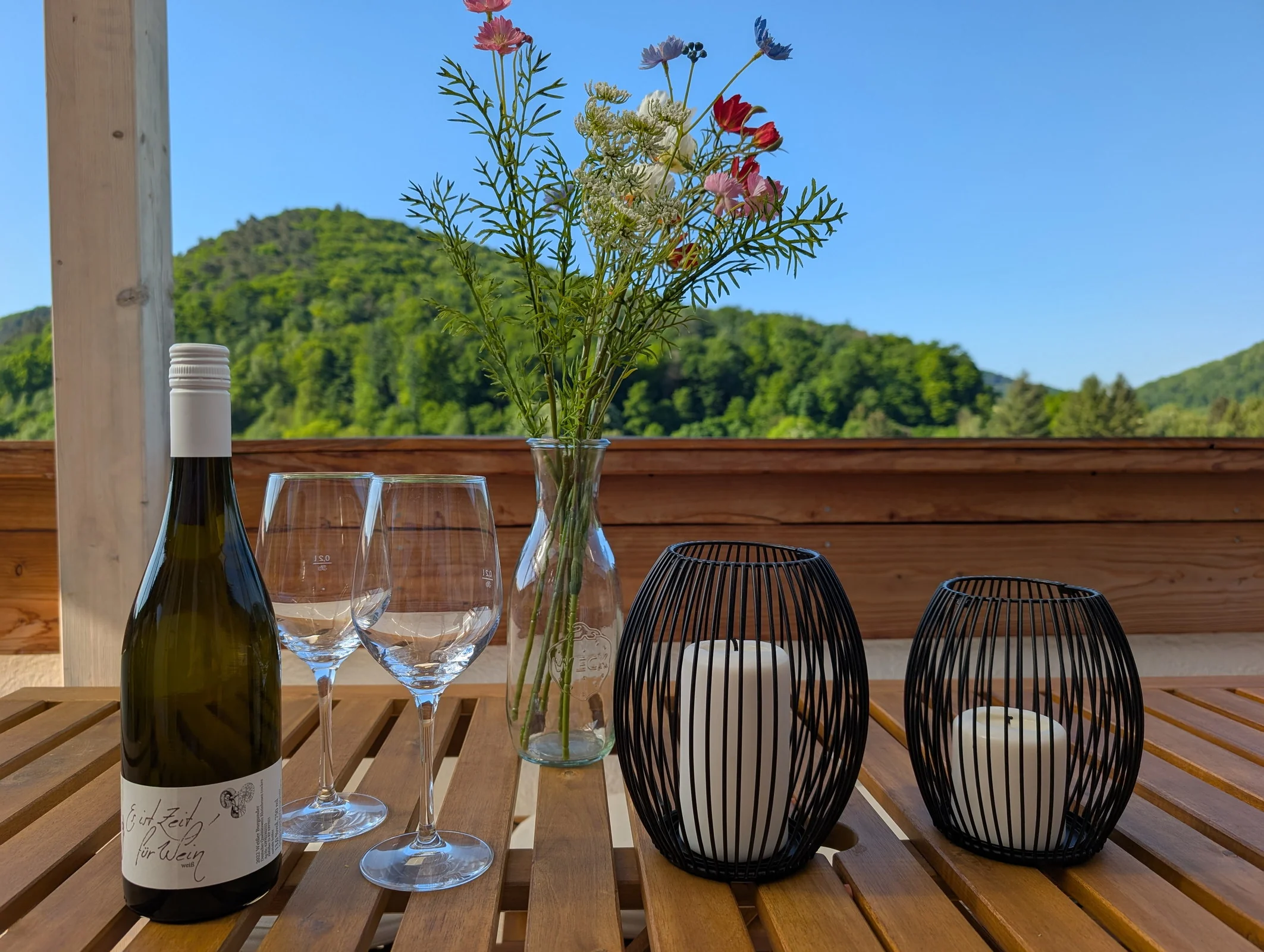 Wein, Gläser und Blumen auf dem Balkontisch vor dem grünen Neckartal